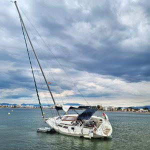 Damaged sailboat leaning in water near shoreline